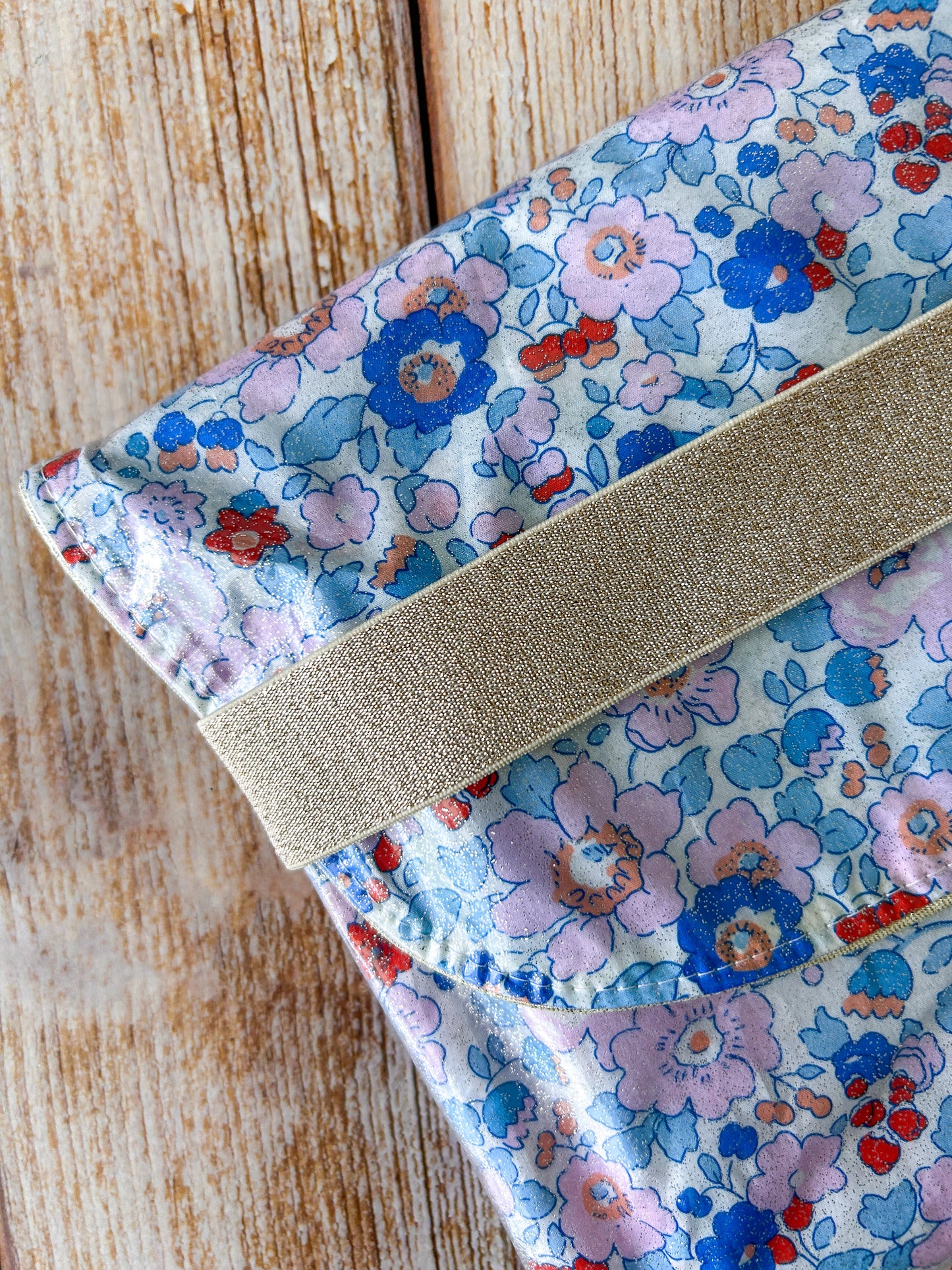 Pochette Liberty Betsy fait main posée sur bois blanc avec lunettes de soleil et parfum, idéale plage et voyage