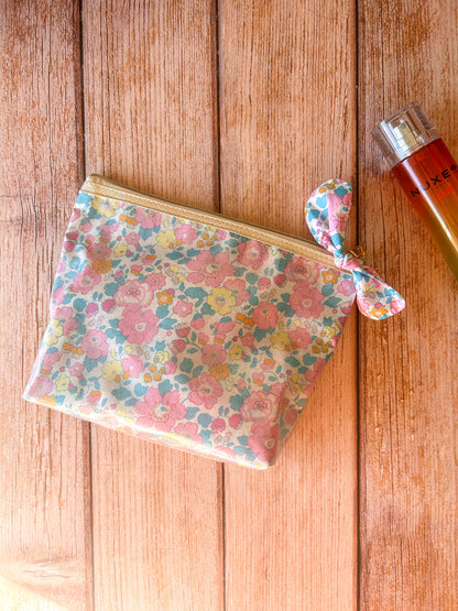 Trousse de voyage transparente en tissu Liberty fleuri pour ranger maquillage, produits de beauté et accessoires.